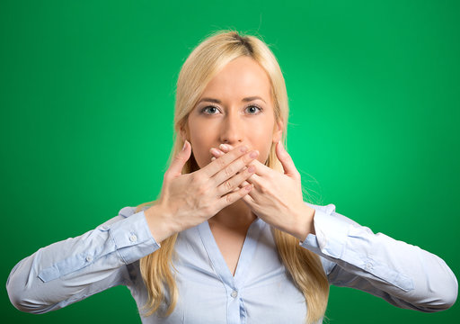 woman covering closed mouth with hands green background 