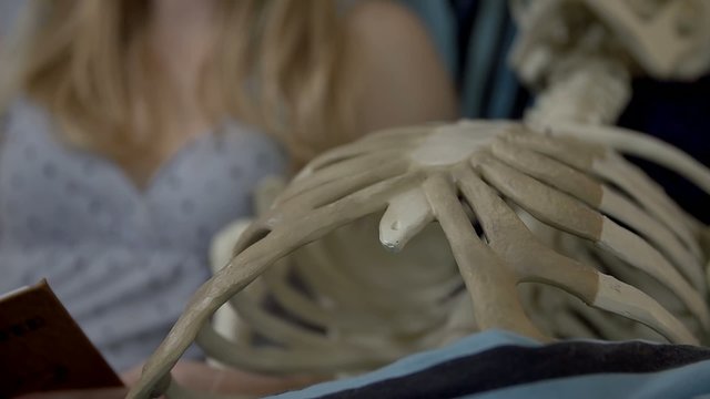 Close shot of woman reading to a skeleton
