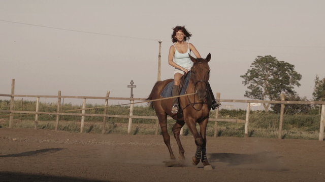 Young woman riding a horse on a lunging rein