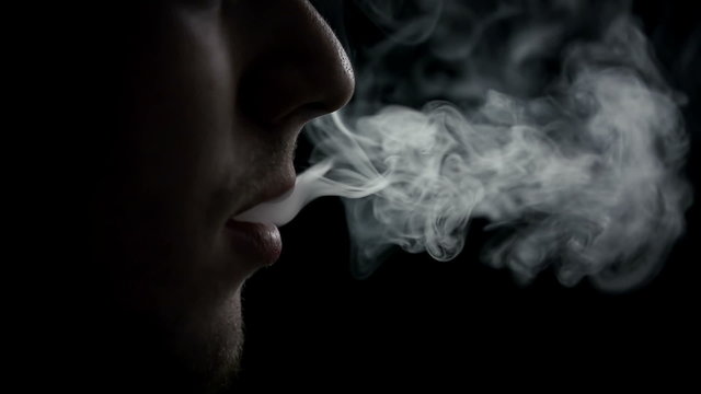 Male during exhaling a cigarette smoke in slo-mo