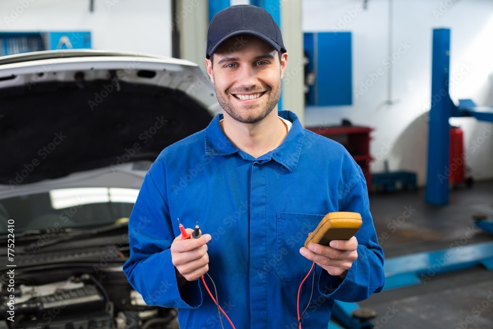 Poster mechanic smiling at the camera holding tool