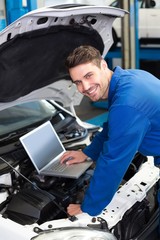 Fototapeta premium Mechanic using laptop on car