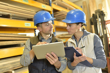 Worker with overseer controling stock in warehouse