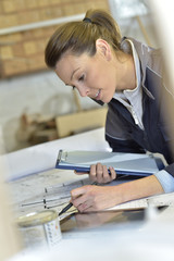 Naklejka premium Young woman carpenter designing plans in workshop