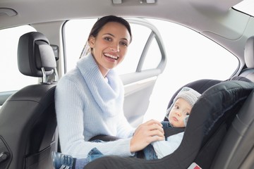 Mother securing her baby in the car seat