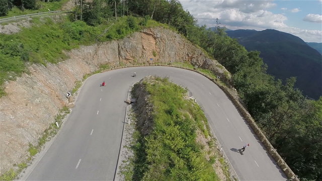 Longboard skaters speeding downhill one after another