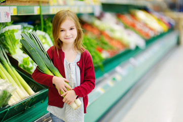 Little girl choosing a leek in a store