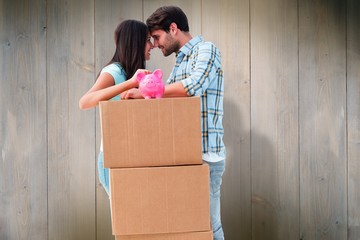 Happy young couple with moving boxes and piggy bank