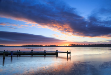 Fototapeta na wymiar Colorful sunrise at a jetty on a winter day.