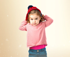 Little girl putting on a Christmas hat over white background