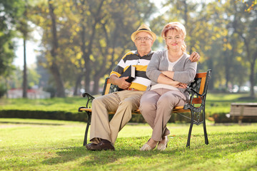 Mature couple relaxing seated on a bench in park