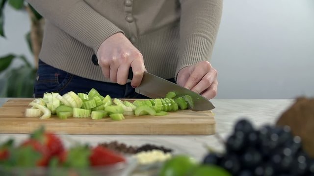 Slicing celery on wooden cooking desk

