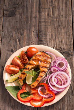 Grilled salmon steak with sliced onion and tomatoes vertical