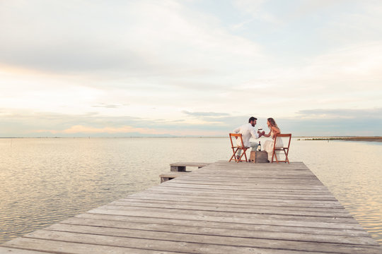 couple drinking red wine at the seaside on a jetty