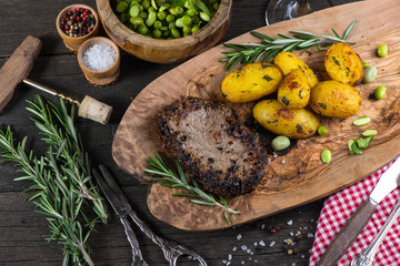 Beef steak with roasted potatoes and herbs, top view