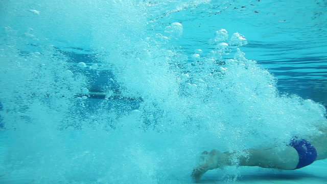 Girl jumping into a pool and swimming under water