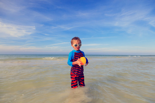 little boy playing ball on the beach