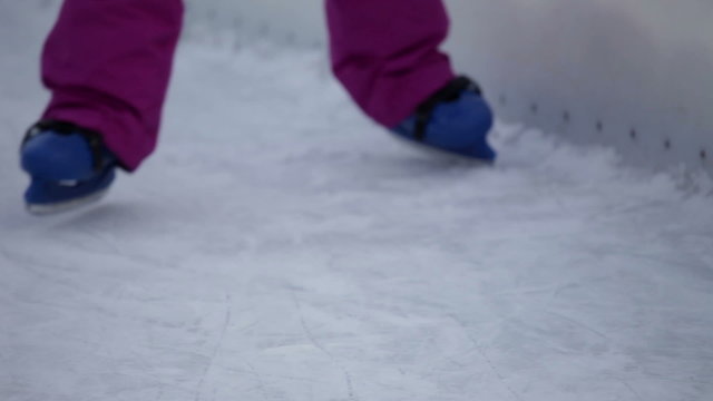 Detail shot of blue kiddie skates staggering on ice rink
