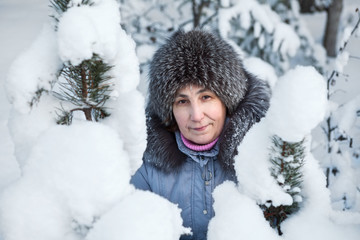 Fototapeta premium Woman face in beauty snowy pine branches at winter season