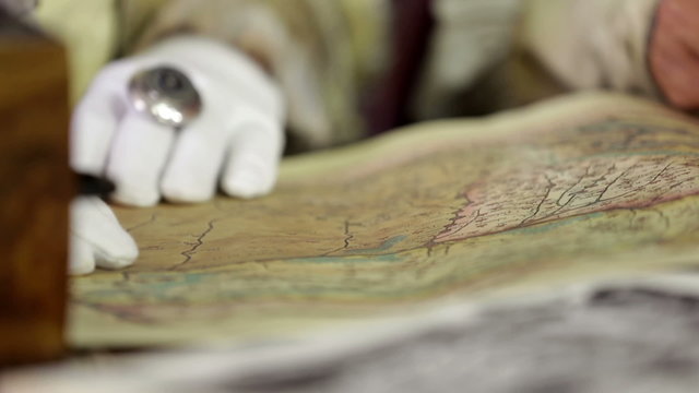 Studying an old map while following a road with his finger