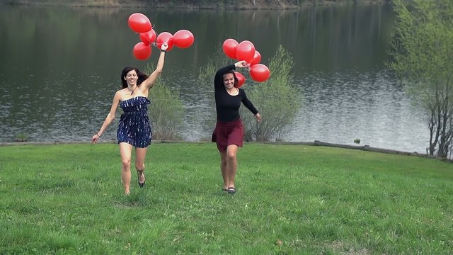 Two Girls Enjoying Life Running With Red Balloons In Dresses