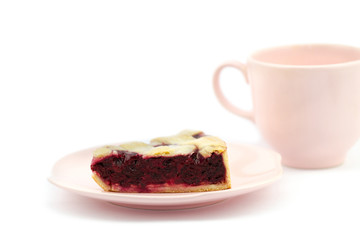 Slice of fresh baked cherry pie on a plate with pink cup