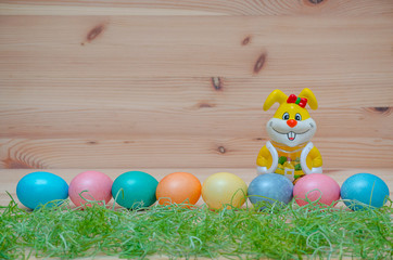 happy bunny with easter eggs and grass on the wooden background