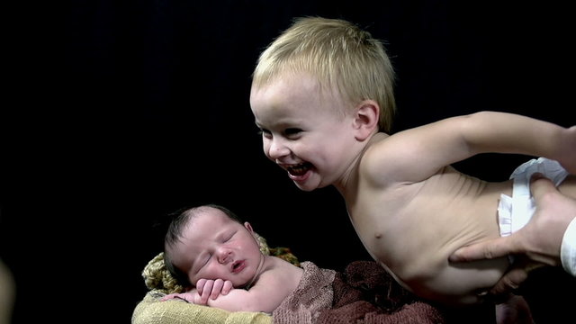 Small kid laughing loudly while being held above his baby brother