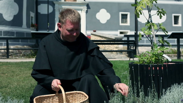 Medium shot of monk picking herbs in front of monastery