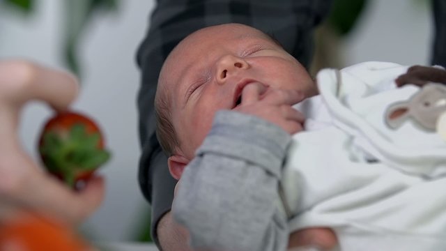 Holding the baby offering a strawberry
