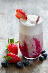 Fresh milk shake with syrup and berries in glas