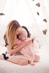 Fototapeta na wymiar Beautiful young woman with small daughter sitting on bed