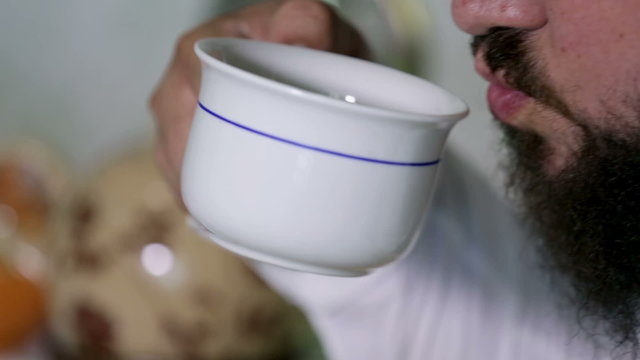 Detail shot of man blowing into a tea and taking a sip