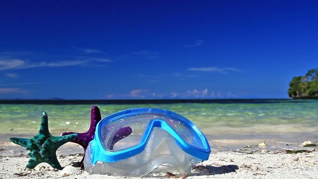 Swimming mask on white sand on tropical beach