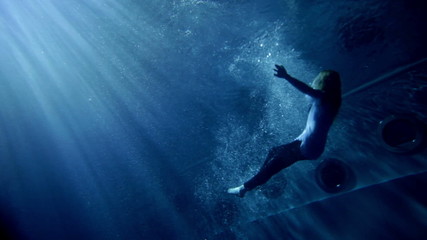 underwater activity and young woman in clothes swimming under water