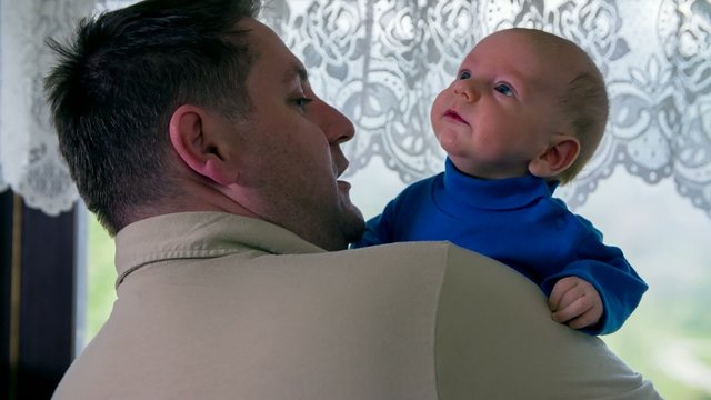 Newborn baby on father shoulder looking at something
