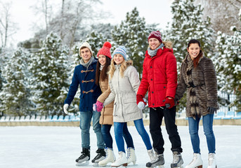 happy friends ice skating on rink outdoors