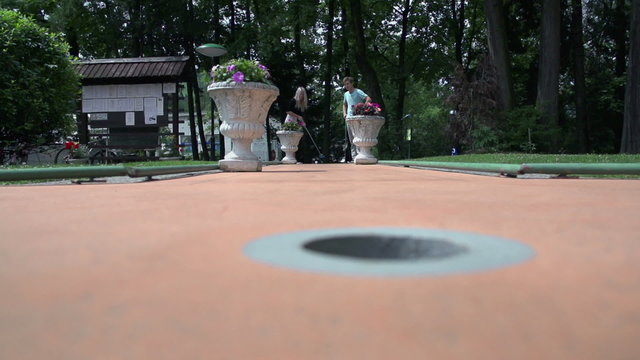 Couple playing mini golf in slow motion
