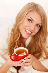 Young woman relaxing in bed with a cup of coffee