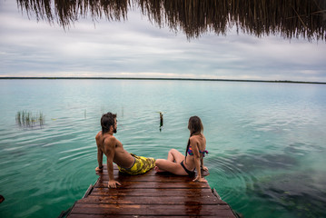 Beautiful couple in love looking at tranquil Bacalar lake.