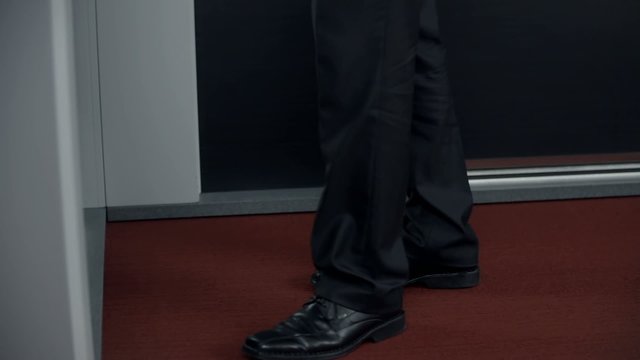 Male person in business clothes stands in front of door
