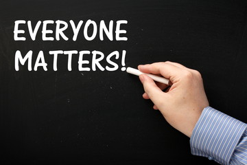 Writing the phrase Everyone Matters on a blackboard