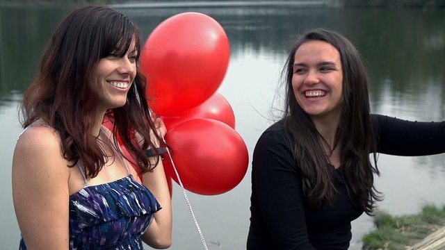 Two Female Friends In Beautiful Dress And With Red Balloons