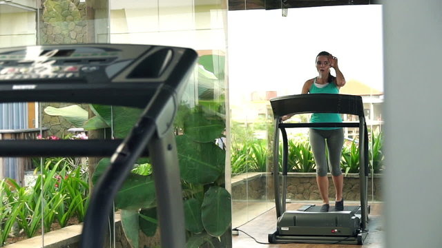 Woman running on treadmill in fornt of the mirror in gym