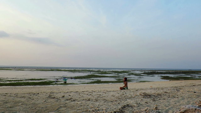 Girl meditating on seashore in lotus position
