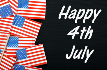 Fototapeta na wymiar The phrase Happy 4th July on a blackboard with USA flags