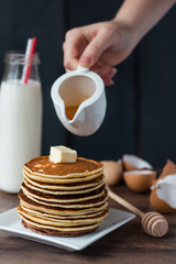 pile of Pancake with butter, pour honey, hand