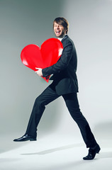 Cheerful young man holding big heart
