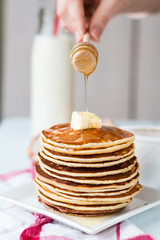 pile of Pancake with butter, honey sauce add,  hands