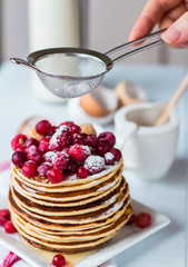 Pancake with cranberries, raspberries and powdered sugar, hands